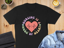 Load image into Gallery viewer, Black t-shirt with "Nursing is a work of heart" text and heart design.