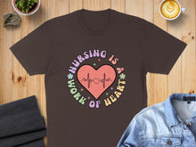 Load image into Gallery viewer, Brown t-shirt with "Nursing is a work of heart" text and heart graphic.