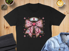 Load image into Gallery viewer, Black t-shirt with a pink bow and nurse cap design featuring hearts and a stethoscope.