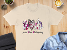 Load image into Gallery viewer, T-shirt with "peace love laboratory" text, graphics of peace sign, heart, and lab equipment.