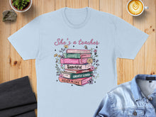 Load image into Gallery viewer, Light blue t-shirt with stack of books and floral design.