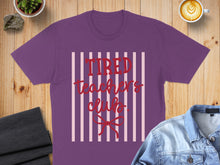 Load image into Gallery viewer, Purple t-shirt with "Tired Teacher's Club" text on striped background.