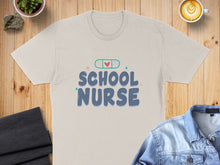 Load image into Gallery viewer, Beige t-shirt with "School Nurse" text and a heart-shaped bandage graphic.