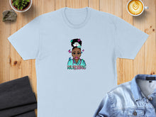 Load image into Gallery viewer, Light blue t-shirt with cartoon nurse graphic, text "NURSING".
