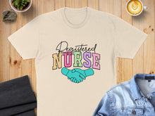 Load image into Gallery viewer, Registered Nurse text with handshake illustration on a light cream t-shirt.
