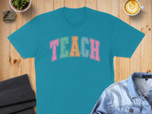Load image into Gallery viewer, Teal t-shirt with "TEACH" in colorful block letters.