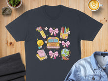 Load image into Gallery viewer, T-shirt with school-themed graphic featuring a bus, globe, books, and crayons.
