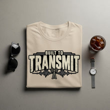 Load image into Gallery viewer, Tan t-shirt with "Built to Transmit" text and radio tower graphic.