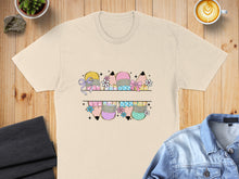 Load image into Gallery viewer, Split image of colorful pencils with bows and flowers on a cream t-shirt.