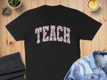 Load image into Gallery viewer, Black t-shirt with "TEACH" text in a floral and star pattern.