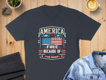 Load image into Gallery viewer, Dark blue t-shirt with "America Land of the Free Because of the Brave" and American flag graphic.
