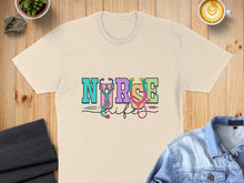 Load image into Gallery viewer, Cream t-shirt with colorful "NURSE LIFE" text and stethoscope graphic.
