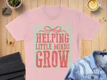 Load image into Gallery viewer, Light pink t-shirt with "Helping Little Minds Grow" text in green and red.
