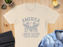 Load image into Gallery viewer, Cream t-shirt with distressed "America 1776 Land of the Free Home of the Brave" graphic.

