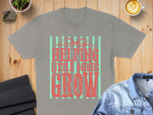 Load image into Gallery viewer, Gray t-shirt with "Helping Little Minds Grow" text and bow design.
