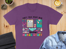Load image into Gallery viewer, Purple t-shirt with "Can't talk right now, doing nurse stuff" and medical icons.
