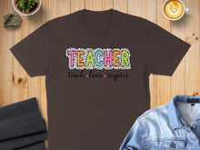 Load image into Gallery viewer, Brown t-shirt with "TEACHER" in colorful polka dot lettering and "teach love inspire" below.
