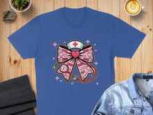 Load image into Gallery viewer, Blue t-shirt with a pink bow, stethoscope, and nurse cap graphic.
