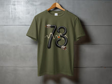 Load image into Gallery viewer, Olive t-shirt with graphic of number 73 made from a coiled cable.
