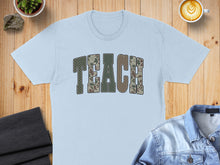 Load image into Gallery viewer, Light blue t-shirt with "TEACH" in camouflage letters.
