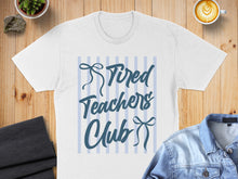 Load image into Gallery viewer, White t-shirt with "Tired Teachers Club" text on blue striped background.
