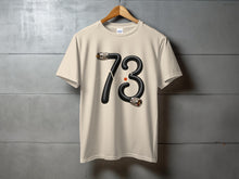 Load image into Gallery viewer, Cream t-shirt with black cable forming the number 73.

