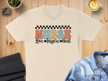 Load image into Gallery viewer, Light beige t-shirt with "Nurse Love Inspire Heal" text and checkered border.

