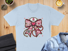 Load image into Gallery viewer, Light blue t-shirt with a pink bow featuring XOXO, a stethoscope, and a heart-shaped bandage.
