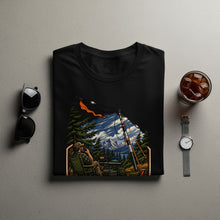 Load image into Gallery viewer, Black t-shirt graphic shows a man operating radio in a mountain forest setting.
