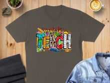 Load image into Gallery viewer, T-shirt with colorful "made to TEACH" graphic featuring school supplies.

