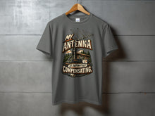 Load image into Gallery viewer, Grey t-shirt with "MY ANTENNA IS DEFINITELY COMPENSATING" text and radio equipment graphic.
