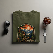 Load image into Gallery viewer, Olive green t-shirt with graphic of man using radio in mountain landscape.
