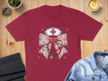 Load image into Gallery viewer, Burgundy t-shirt featuring a pink bow with hearts, stethoscope, and nurse cap graphic.
