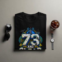 Load image into Gallery viewer, Black t-shirt with "73 AND" graphic featuring globe and radio equipment.
