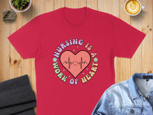 Load image into Gallery viewer, Red t-shirt with "Nursing is a work of heart" graphic and a heartbeat EKG.
