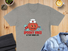 Load image into Gallery viewer, Grey t-shirt with spooky pumpkin, medical supplies, and "Spooky Vibes &amp; That Nurse Life" text.
