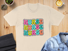 Load image into Gallery viewer, Cream t-shirt with colorful "NURSE" text design, laid flat.
