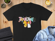 Load image into Gallery viewer, Black t-shirt with colorful "Teacher" text and school supplies graphic.
