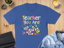 Load image into Gallery viewer, Blue t-shirt with "Teacher You Are" in colorful letters, surrounded by crayon designs.

