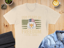 Load image into Gallery viewer, Cream t-shirt featuring eagle wearing bandana, American flag, and text "250 YEARS OF FREEDOM 1776-2026".
