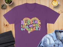 Load image into Gallery viewer, Purple t-shirt with "Nursing is a work of heart" rainbow text and flowers.
