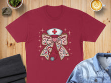 Load image into Gallery viewer, Red t-shirt with a graphic of a stethoscope and nurse's cap forming a bow.
