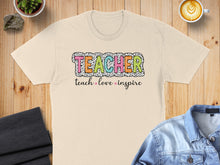Load image into Gallery viewer, T-shirt with "TEACHER" in colorful letters, "teach love inspire" below.

