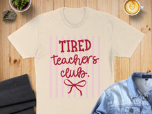 Load image into Gallery viewer, Cream t-shirt with "Tired Teachers Club" and a red bow graphic.
