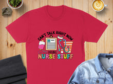 Load image into Gallery viewer, Red t-shirt with "Can't talk right now, doing nurse stuff" text and nurse graphics.
