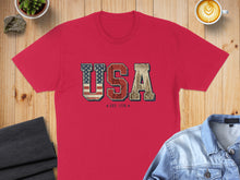 Load image into Gallery viewer, Red t-shirt with "USA EST. 1776" text featuring a skyscraper and American flag graphic.
