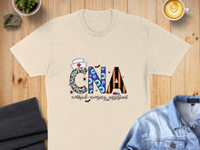 Load image into Gallery viewer, CNA Certified Nursing Assistant text with eye graphics and stethoscope on a cream t-shirt.
