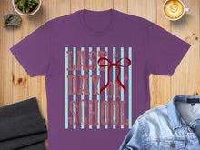 Load image into Gallery viewer, Purple t-shirt with "Last Day of School" text and red bow on striped background.
