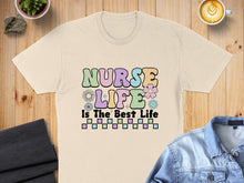 Load image into Gallery viewer, "Nurse Life Is The Best Life" text with pastel letters, flowers, and checkered pattern on a beige t-shirt.
