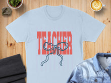 Load image into Gallery viewer, Light blue t-shirt with red "TEACHER" text and a blue bow graphic.
